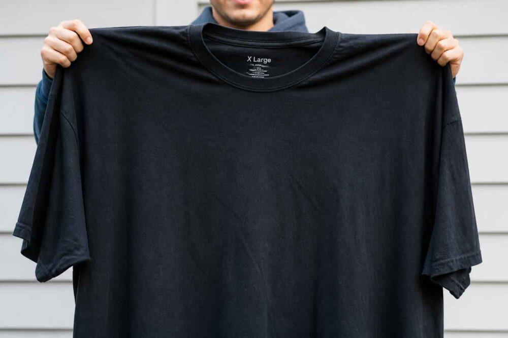 Osoba trzymająca rozłożony czarny T-shirt z krótkim rękawem	gr 重庆时时彩彩