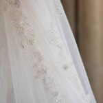 Zbliżenie na biały welon ślubny z koronką i delikatnymi zdobieniami kryształkami